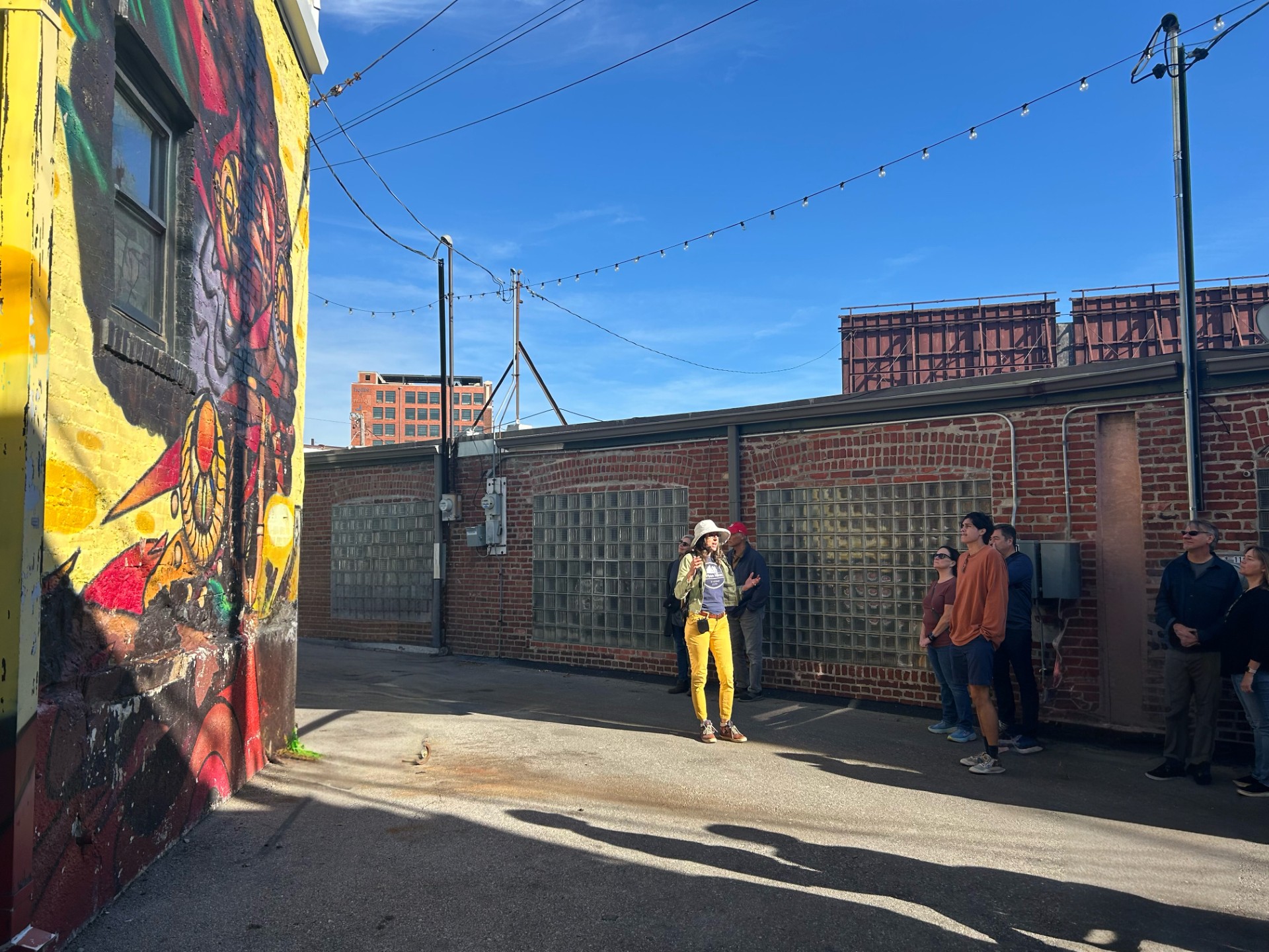 image of a group of young individuals standing in an alley in downtown kansas city and looking at a colorful graffiti mural